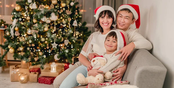 Feliz familia sentada bajo el árbol de Navidad —  Fotos de Stock