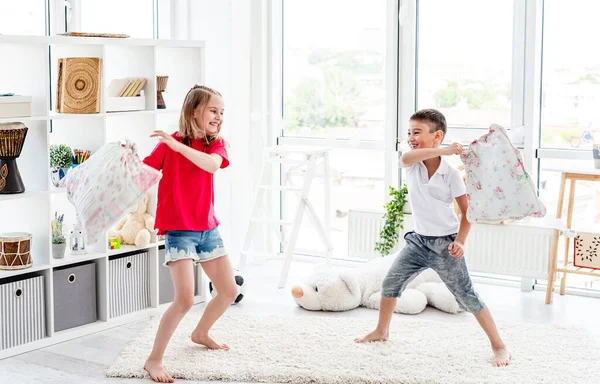 Смеющиеся дети веселятся во время битвы подушками — стоковое фото