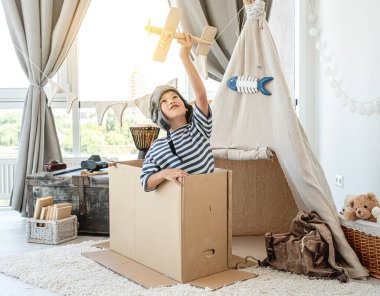 Küçük çocuk tahta uçak uçuruyor.