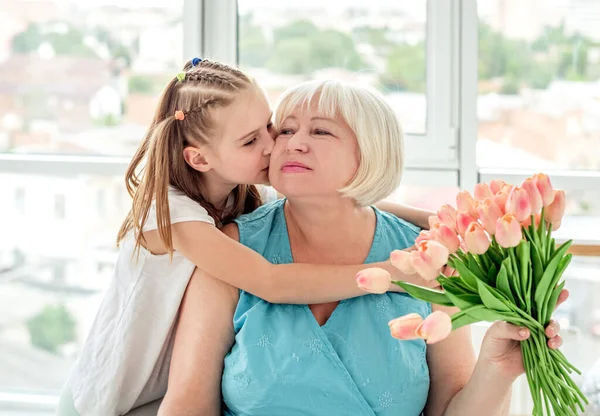 Hübsches kleines Mädchen küsst glückliche Großmutter — Stockfoto