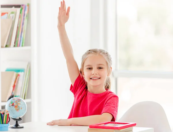 Smiling schoolgirl raising hand during lesson — Stock Photo, Image