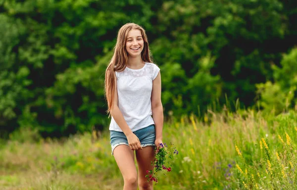 Chica sonriente con ramo de flores de campo — Foto de Stock