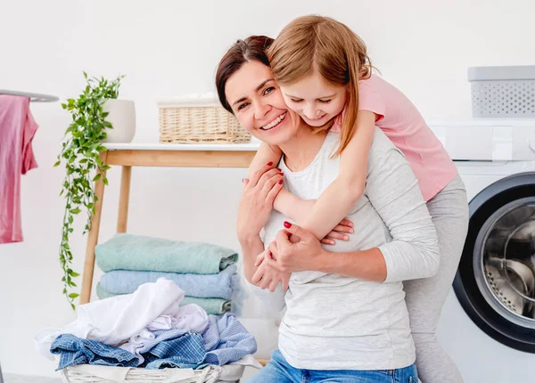 Niña abrazándose con la madre durante la colada — Foto de Stock