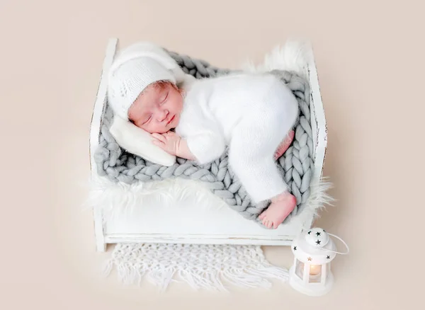 Милый новорожденный спит на крошечной кровати — стоковое фото