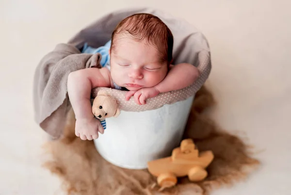 Newborn sleeping in cradle holding toy — Stock Photo, Image