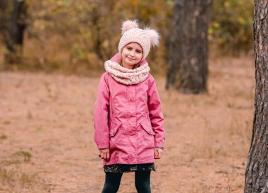 Küçük kız örgü atkı ve şapka takıyor.