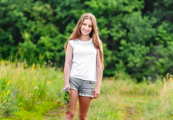 Smiling girl with field flowers bouquet — Stock Photo, Image