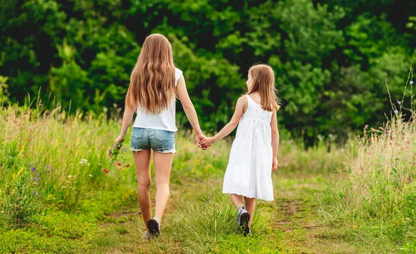 Meisjes wandelen hond langs de grond weg — Stockfoto