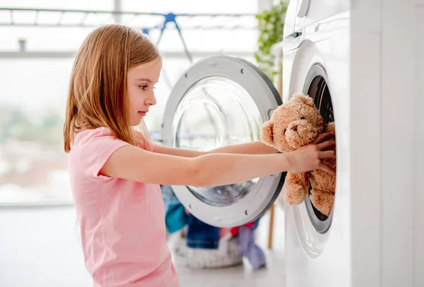 Niña poniendo juguete en la lavadora — Foto de Stock