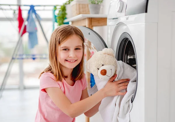 Klein meisje nemen van speelgoed uit wasmachine — Stockfoto