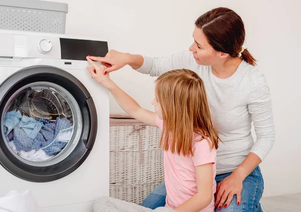 Madre enseñanza hija operar lavadora — Foto de Stock