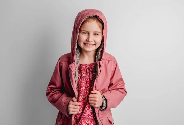 Klein meisje in roze jasje staand binnen — Stockfoto