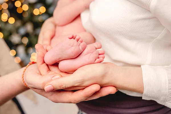 Bara fötter av nyfödda omgivna av familjemedlemmar händer — Stockfoto