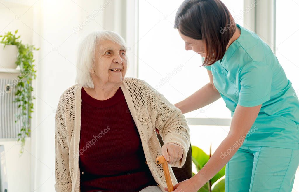 Nurse giving cane to old woman