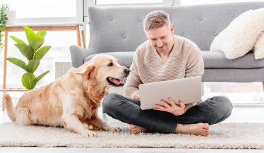 Dizüstü bilgisayarı ve golden retriever köpeği olan adam.