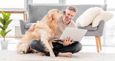 Dizüstü bilgisayarı ve golden retriever köpeği olan adam.