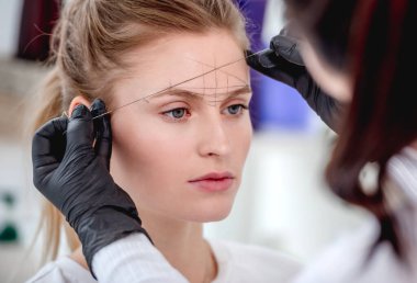 Usta kaşlarını kalıcı makyaj yapıyor.