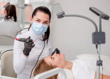 Usta kaşlarını kalıcı makyaj yapıyor.