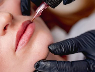 Usta dudakları kalıcı makyaj yapıyor.