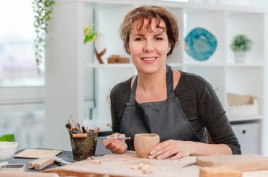 Gülümseyen kadın çömlekçi atölyede çalışıyor