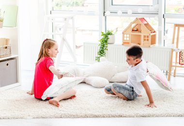 Küçük oğlan ve kız yastıklarla savaşıyor.