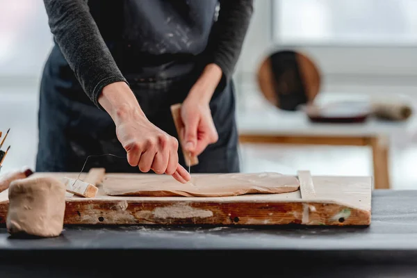 Mujer cortando arcilla usando alambre en el taller — Foto de Stock