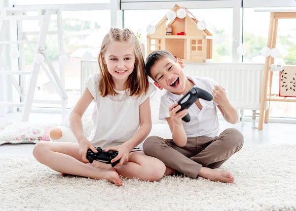 Petite fille et garçon jouant sur console — Photo