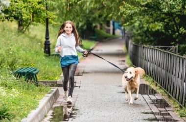 Genç kız yağmurdan sonra köpekle koşuyor.