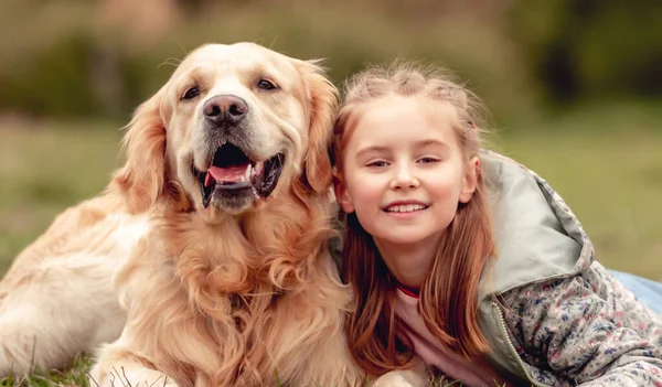 Lille pige med gylden retriever hund udenfor - Stock-foto