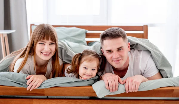 Rodina pod dekou v posteli — Stock fotografie