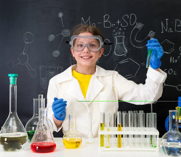 Schoolgirl in white gown doing experiments with liquids — Stock Photo, Image