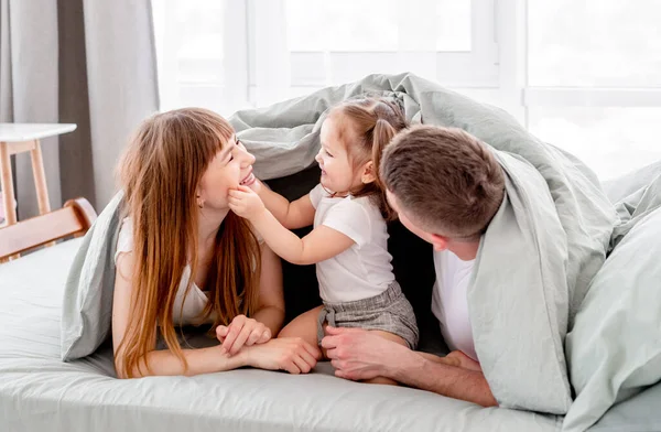 Familia bajo la manta en la cama — Foto de Stock