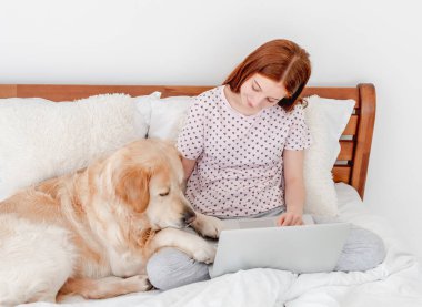 Dizüstü bilgisayarı ve golden retriever köpeği olan kız.