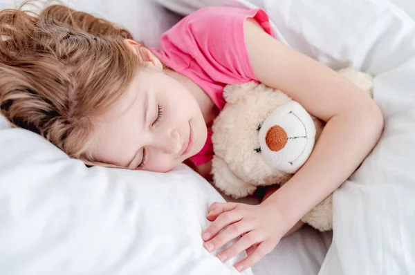 Oyuncak ayıyla yatakta bir kız — Stok fotoğraf