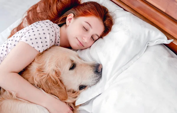 Menina com cão golden retriever na cama — Fotografia de Stock