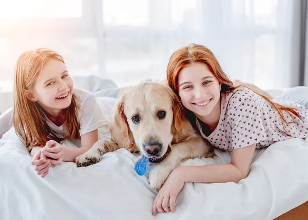 Κορίτσια με χρυσό σκύλο ριτρίβερ στο κρεβάτι — Φωτογραφία Αρχείου