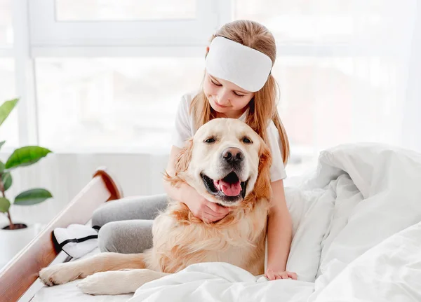Meisje met golden retriever hond in het bed — Stockfoto