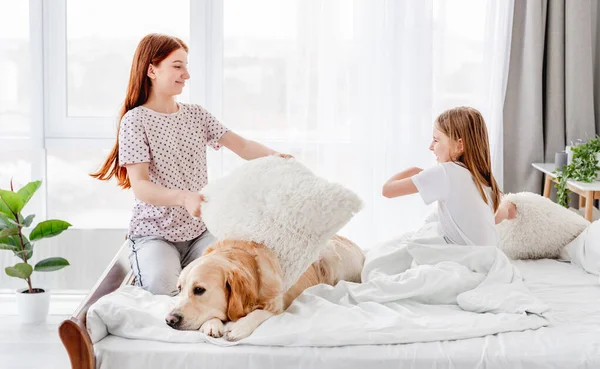 Zusters in bed met golden retriever hond — Stockfoto