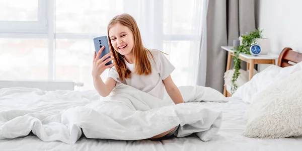 Menina com smartphone na cama — Fotografia de Stock