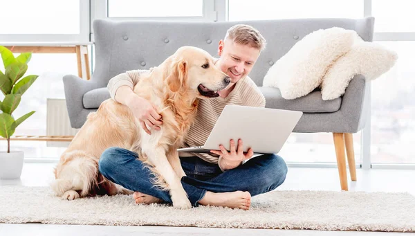 Hombre con portátil y perro golden retriever —  Fotos de Stock