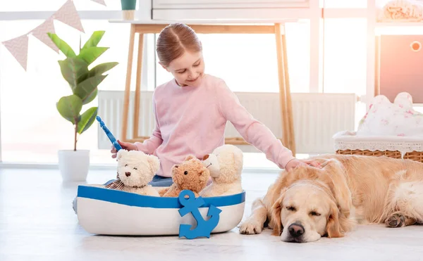 Κοριτσάκι παιχνίδι με το πλοίο με το σκυλί golden retriever — Φωτογραφία Αρχείου