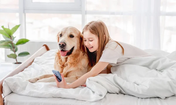 Menina com cão golden retriever e smartphone — Fotografia de Stock