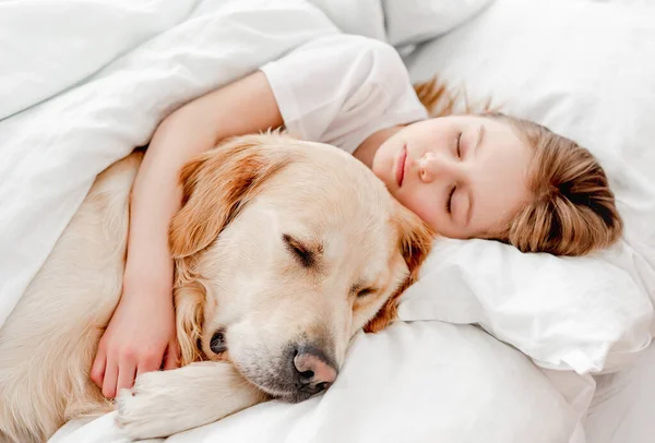 Chica con perro golden retriever en la cama — Foto de Stock