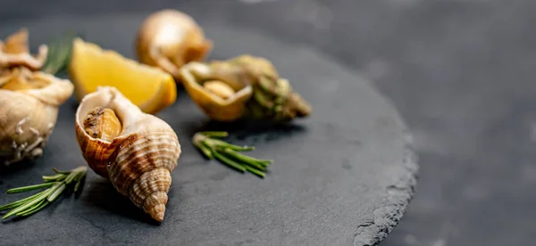 Snails with lemon on black platter — Stock Photo, Image