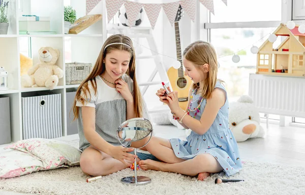 Glada barn leker med makeup läppstift — Stockfoto