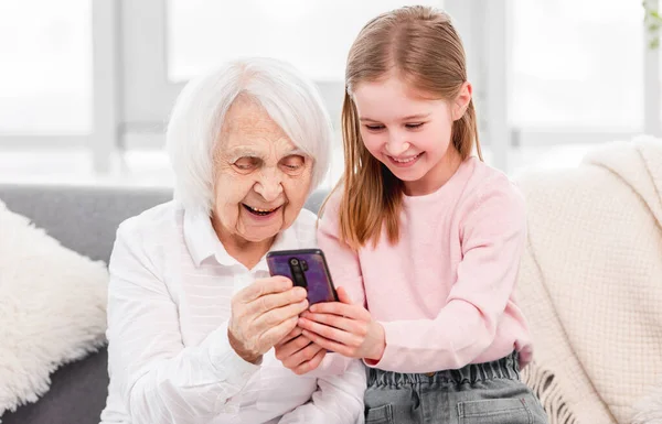 Mormor med dotterdotter använder smartphone — Stockfoto