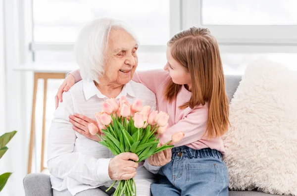 Grandaughter gives flowers to grandmother — Stock Photo, Image