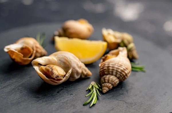 Snails with lemon on black platter — Stock Photo, Image