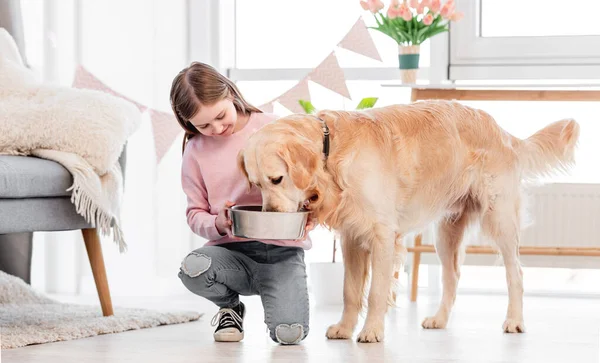 Mała dziewczynka karmi psa golden retriever — Zdjęcie stockowe