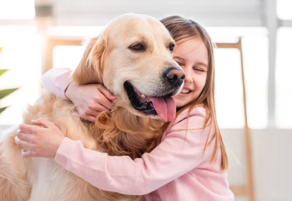 Petite fille caressant chien golden retriever — Photo